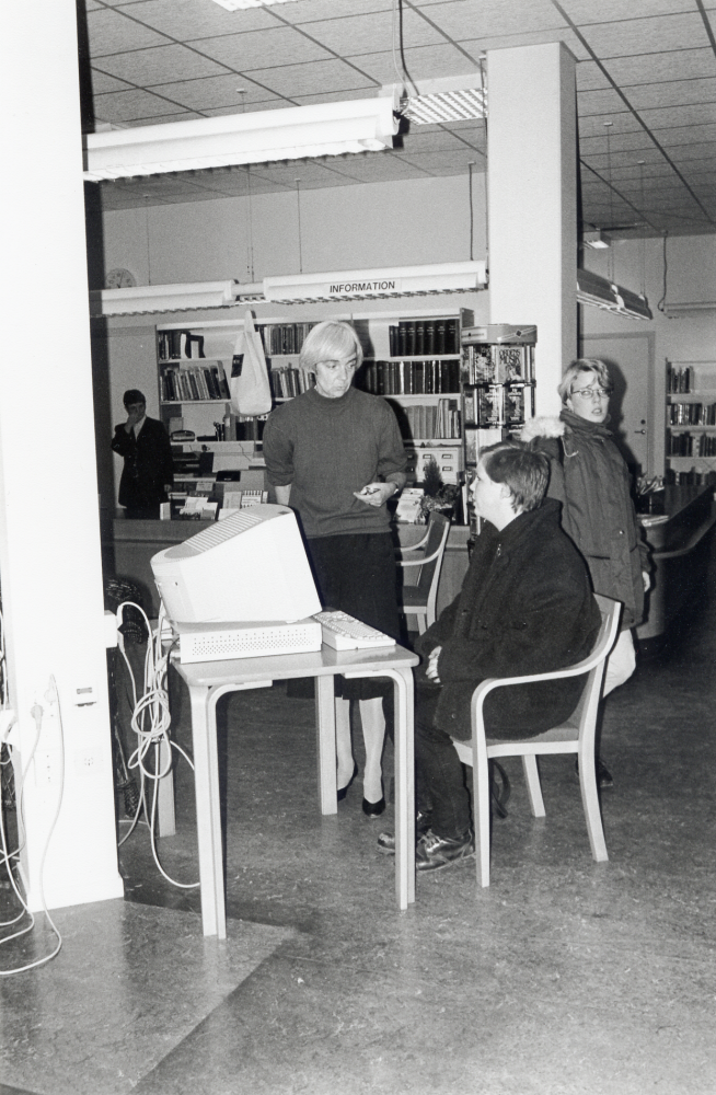 Vallentuna bibliotek datoriseras med system Btj 2000.  Biblioteket har varit stängt till kl 17.00.  Då öppnas dörrarna och vallentunaborna kan låna och söka litteratur på ett helt nytt sätt med datorernas hjälp.  Vid datorn sitter en låntagare som får hjälp av Anna Brynell.  Bakom disken t v står Bibliotekstjänsts instruktör Monica Wiksten-Engstrand