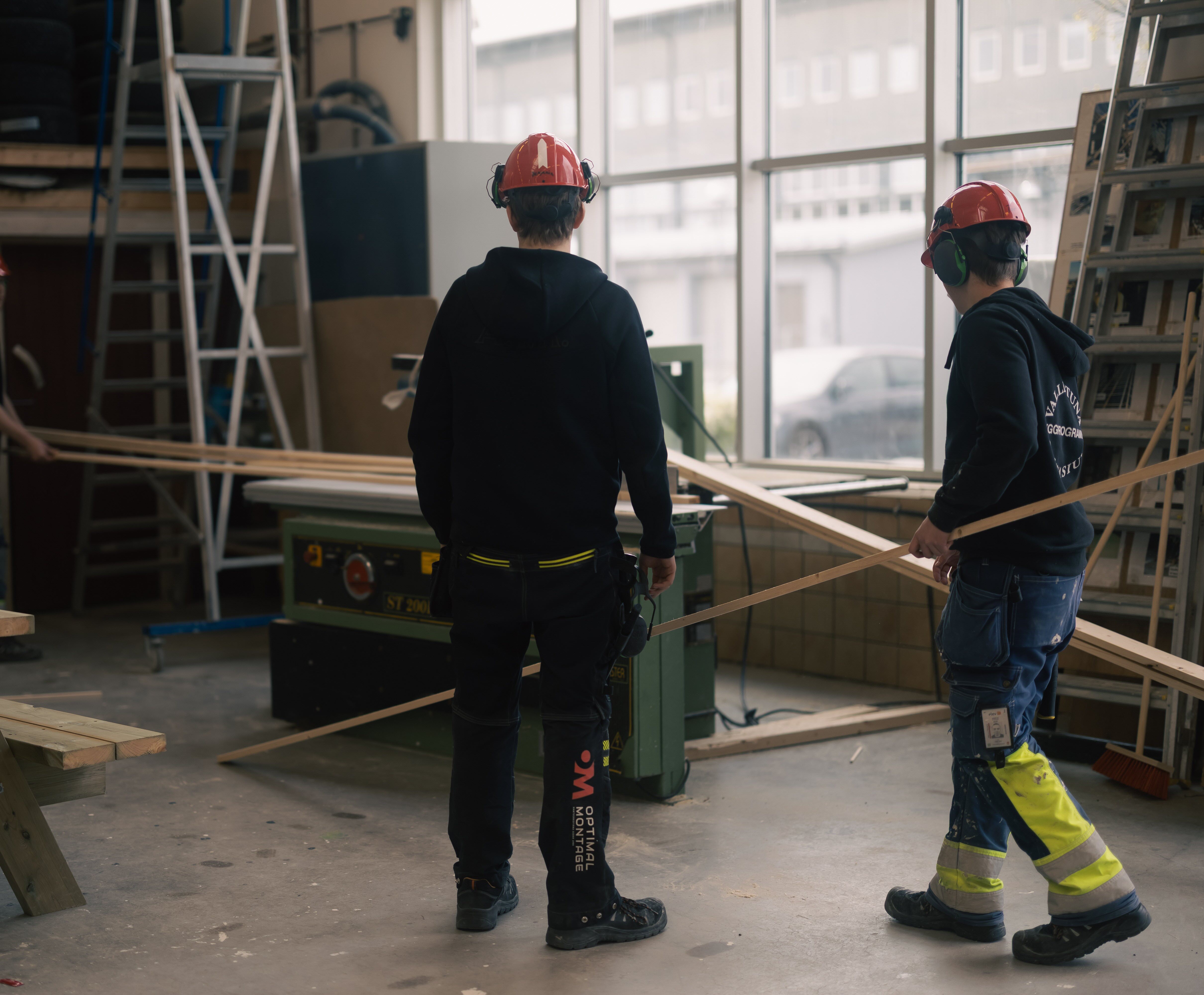 Två elever använder en sågmaskin för brädor.