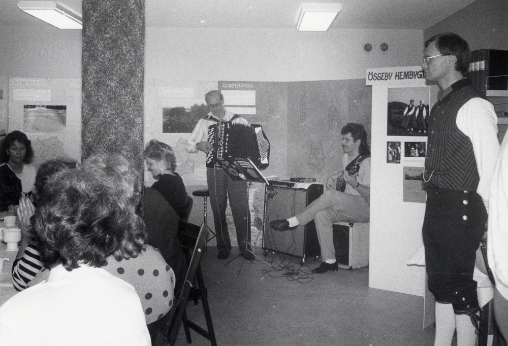 Karby bibliotek har reparerats sommaren 1987 och invigs med öppet hus 25 oktober. I hyresgästlokalen bredvid biblioteket serveras kaffe, visas utställningar och bjuds på musik. Här spelar Särdraget, Pelle Andersson med dragspel och sonen Sven Andersson med elgitarr.  Stående t h Börje Sjöman, ordförande i Össeby hembygdsförening